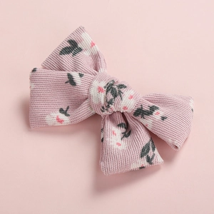 Close-up of pink corduroy bow hair clip with floral pattern and textured fabric detail