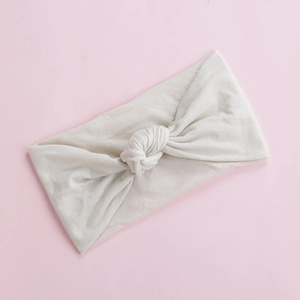 Detail view of cream white knotted baby headband in soft elastic nylon fabric