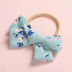 Detailed texture of light blue floral corduroy bow with highly elastic nude nylon band