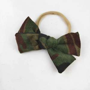 Detail of baby bow headband featuring green camo corduroy fabric and elastic nylon band