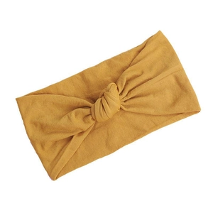 Soft nylon baby headband with knot design in mustard yellow color on white background