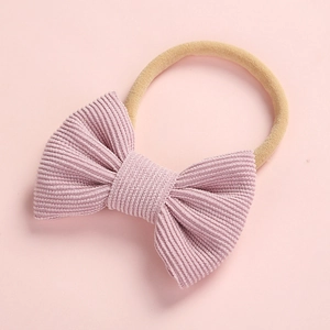 Détail du nœud en velours côtelé rose et du bandeau élastique doux en nylon pour bébé