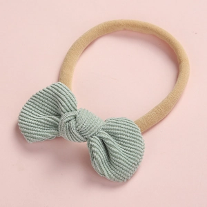 Détail du nœud en velours côtelé vert menthe sur un bandeau souple en nylon pour bébé