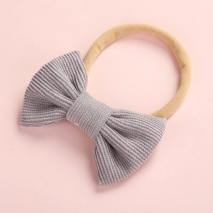 Bandeau bébé avec nœud en velours côtelé gris et élastique sur fond rose tendre