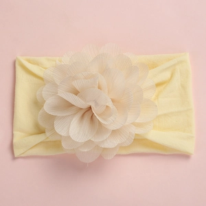 Detail of soft yellow nylon baby headband with a large layered organza flower on pink background