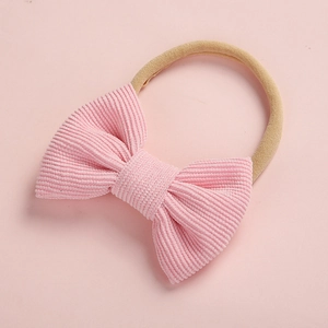 Détail du nœud en velours côtelé rose et du bandeau souple en nylon bébé