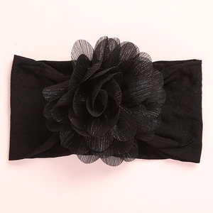 Detailed view of black elastic baby headband with large layered mesh flower and glitter