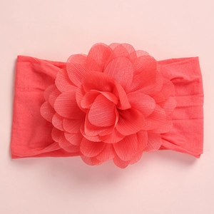 Detailed close-up of coral pink chiffon flower and wide soft nylon headband for babies