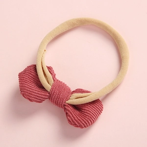 Détail du nœud en velours côtelé bordeaux avec bandeau pour bébé en nylon beige doux