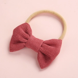 Détail d'un nœud en velours côtelé rose sur un bandeau en nylon souple pour bébés