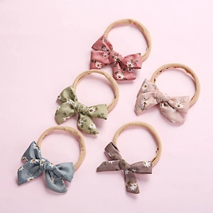 Detailed view of five floral corduroy bow baby headbands in wine red and pastel tones