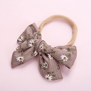 Detail of soft nylon infant headband with a brown floral bow featuring daisy prints