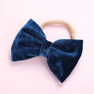 Close-up of baby headband with royal blue velvet bow and soft nude nylon elastic band