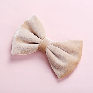 Macro shot showing soft champagne velvet fabric texture of the large bow hair clip