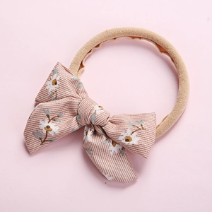 Close-up of floral bow baby headband with soft elastic nylon and corduroy texture detail