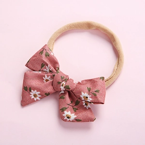 Detailed macro view of high-elasticity nylon headband with soft pink floral bow for babies