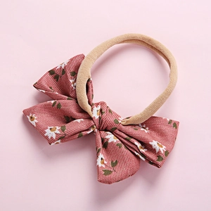 Close-up of pink floral baby headband with white daisy print and soft elastic nylon band