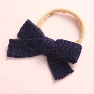 Close-up of handmade navy knit bow headband with elastic nylon band for babies