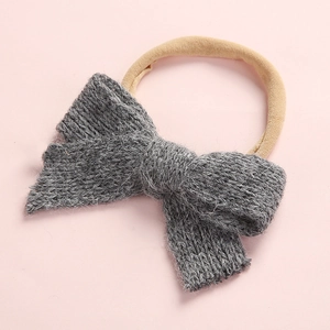Detailed close-up of dark grey knitted bow with soft beige elastic headband for infants