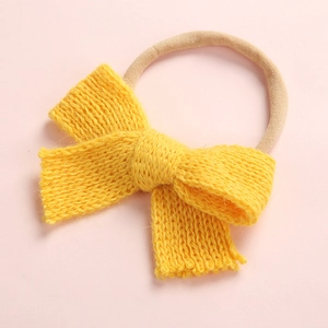 Detail of yellow knitted bow headband for babies with soft elastic skin-toned band