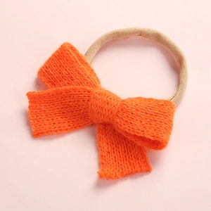 Close-up of bright orange knitted baby headband with a soft bow and elastic band