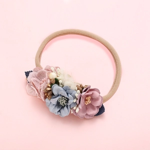 Vue détaillée de fleurs en tissu et perles sur un bandeau en nylon pour bébé