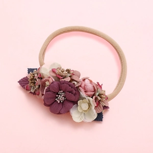 Détail d'un bandeau pour bébé en nylon avec des fleurs en tissu colorées et des feuilles