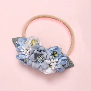 Détail d'un bandeau à fleurs en maille fait main avec des pétales bleus et blancs sur rose