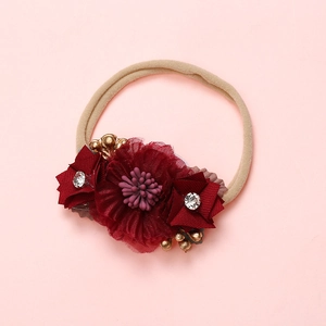 Détail d'un bandeau bébé avec fleurs en tulle bordeaux, pétales en soie et strass