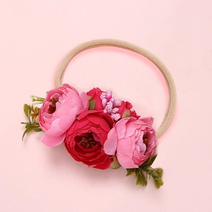 Détail de trois fleurs en soie roses et rouges avec baies sur bandeau bébé élastique