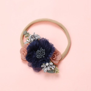 Détail d'un bandeau pour bébé avec fleurs en maille bleu marine et rose fait main