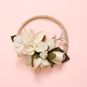 Détail de fleurs artificielles crème et rose sur bandeau souple pour bébé