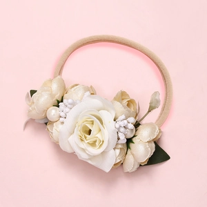 Détail macro du bandeau bébé à fleurs crème avec perles et pétales de rose en soie