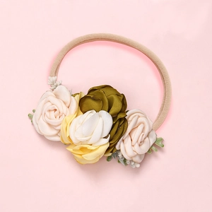 Détail d'un bandeau pour bébé avec fleurs en satin sur un ruban de nylon rose doux