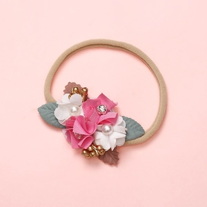 Détail du bandeau bébé avec fleurs en satin rose, perles et feuilles en tissu vert