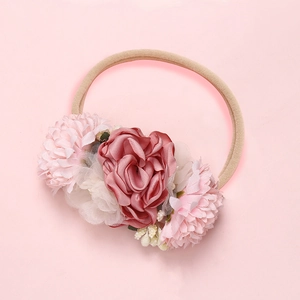 Détail d'un bandeau fleur rose fait main avec bande en nylon souple pour bébés filles