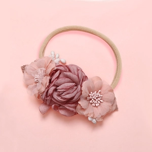 Détail d'un bandeau pour bébé en nylon souple avec fleurs en tissu rose faites à la main