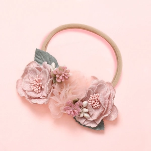 Vue détaillée du bandeau floral rose fait main pour bébé avec bande élastique en nylon