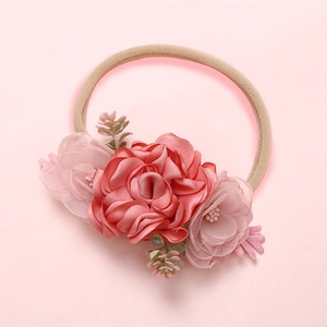 Détail du bandeau bébé avec rose en satin rouge foncé et fleurs en tulle rose sur nylon
