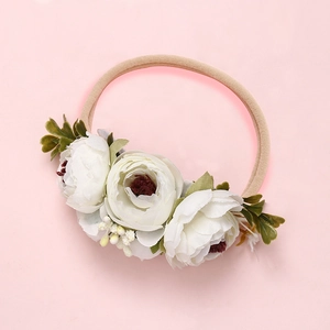 Détails d'un bandeau pour bébé avec des fleurs en tissu blanc et des feuilles vertes
