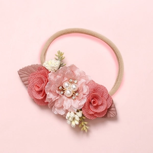 Détail d'un bandeau pour bébé avec perles, strass et fleurs en tissu doux de haute qualité