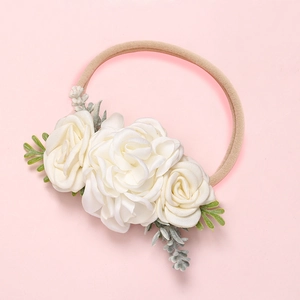Détail du bandeau bébé avec roses en satin blanc et feuilles vertes sur bande nylon