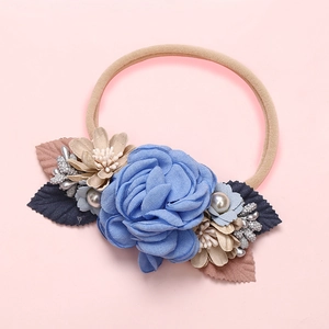 Détail du bandeau bébé avec rose en tissu bleu et perles sur un ruban élastique doux