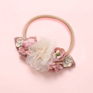 Détail d'un bandeau bébé avec fleurs en mousseline blanche et strass sur ruban souple