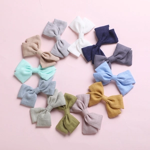 Set of 12 colorful cotton bow hair clips for girls arranged in a circle on pink background