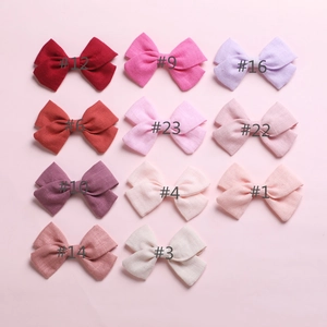 Flat lay of 11 colorful cotton bow hair clips in various pastel and earthy tones
