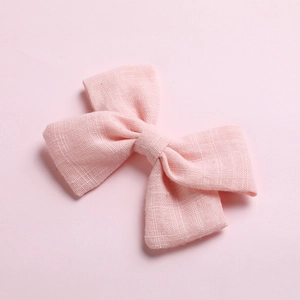 Close-up of pink cotton bow hair clip showing detailed woven fabric texture and soft color