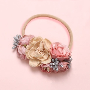 Détail d'un bandeau fleur en maille fait main avec pétales roses et beige et ruban nylon
