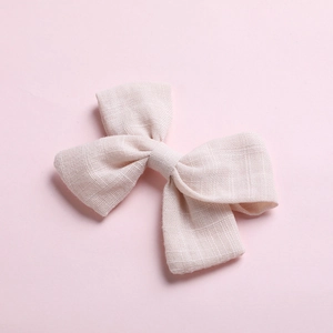 Detail view of pink cotton bow hair clip showing textured fabric and knotted center