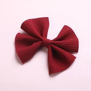 Detail of dark red textured fabric hair bow clip for girls with honeycomb weave